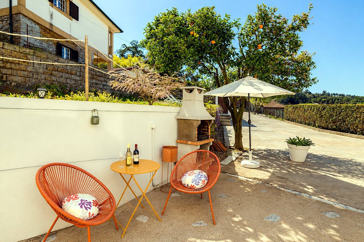 Patio d'Outeiro 1 : chaises orange, barbecue en pierre et oranger — Casa Outeiro 99, Paredes de Coura